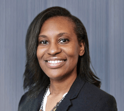Tamia Simons smiles at the camera wearing a black blazer